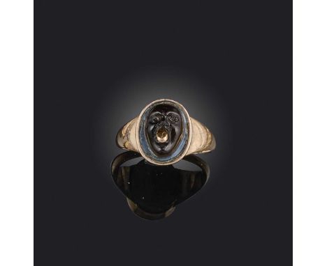 An early 19th century cameo ring, set with a banded agate cameo of a grotesque mask with a gold tongue, in closed back yellow