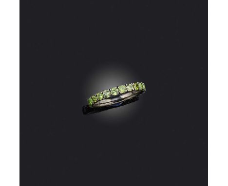 A demantoid garnet eternity ring, set with a continuous line of circular-cut demantoid garnets, mounted in blackened platinum