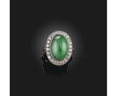 A jadeite and diamond cluster ring, the oval jade cabochon set within a surround of circular-cut diamonds in white gold, stam