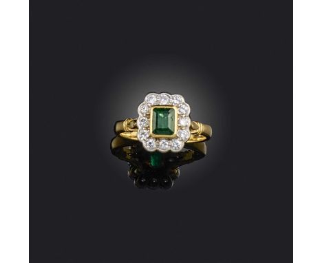 An emerald and diamond ring, of cluster design, set with a step-cut emerald within a border of brilliant-cut diamonds, mounte