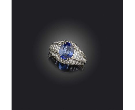 A sapphire and diamond bombé ring, set with an oval sapphire within graduated baguette-shaped and circular-cut diamonds, moun