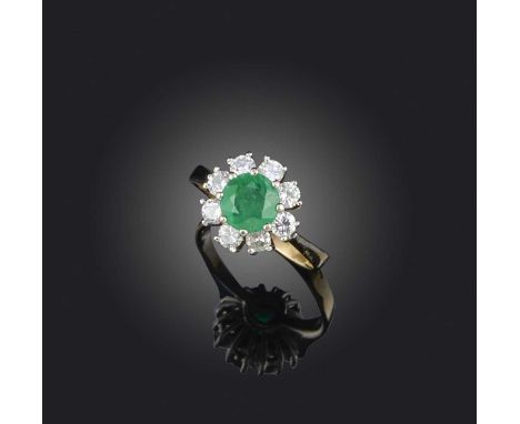 An emerald and diamond ring, of cluster design, set with a circular-cut emerald within a border of brilliant-cut diamonds, mo