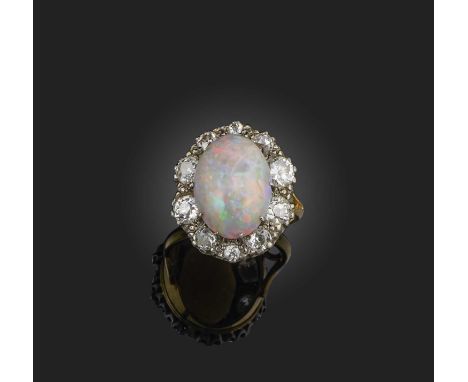 An opal and diamond ring, of cluster design, set with a cabochon opal within a border of circular-cut diamonds, mounted in si