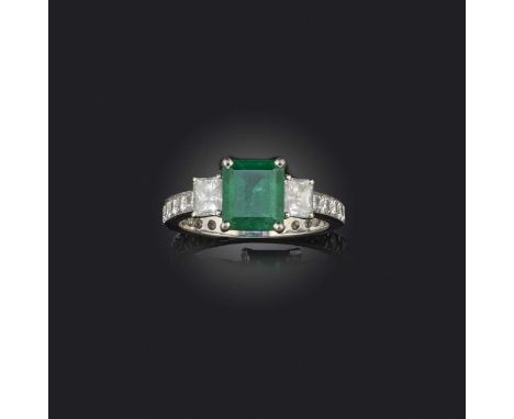 An emerald and diamond ring, claw-set with a step-cut emerald weighing approximately 1.60 carats, between shoulders set with 