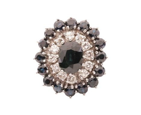 A sapphire and diamond cluster ring, featuring a central oval sapphire measuring 9 x 6.8 x 4.7mm, encircled by a row of round
