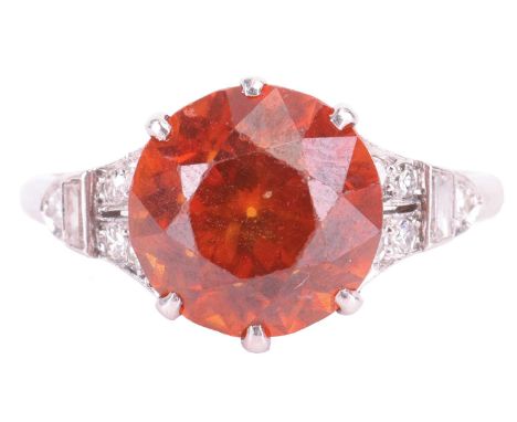 An Art Deco zircon and diamond dress ring, centred with a circular-cut dark orange zircon of 9.4 x 9.4 x 6.8 mm, in claw sett