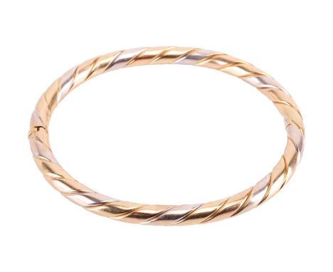 A hinged bangle in 18ct tri-coloured gold, of twisted design, alternating with white, rose and yellow gold, with a concealed 