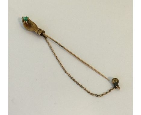 An unusual emerald and diamond stick pin in the form of a hand clutching the stone. Approx. 5 grams. Est. £300 - £400.