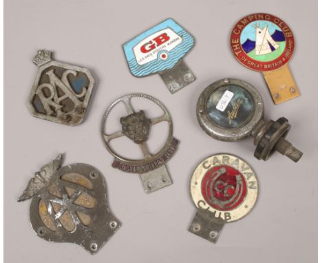 A collection of six vintage automobile radiator badges and an Austin radiator cap.