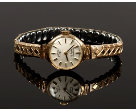 A ladies 9ct gold Rotary manual watch head with baton markers on gold plated expanding bracelet strap.