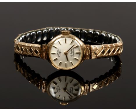 A ladies 9ct gold Rotary manual watch head with baton markers on gold plated expanding bracelet strap.