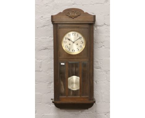 An Edwardian oak cased spring driven wall clock chiming on a coiled gong with pendulum and key.