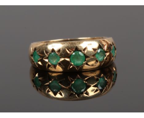 A 9ct gold five stone gypsy ring set with emeralds, size L.