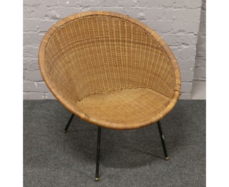 A vintage basketware 1960s chair raised on painted steel legs.