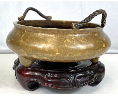 A Chinese mottled bronze censer with twin rope twist handles, on three feet, with seal mark to base, with matching hardwood b