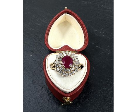 A 9 carat hallmarked gold dress ring set with a central ruby and two concentric tiers of small diamonds, size 'M', 4.5gm. 