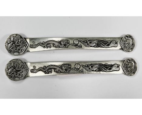 A pair of Chinese white metal embossed scholars scroll weights with impressed marks 