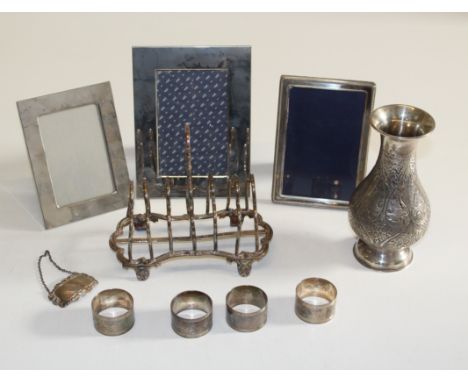 A Victorian silver six slice toast rack, a silver easel photograph frame, four silver serviette rings, a baluster vase stampe