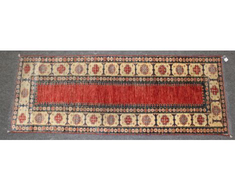 A kazak runner, woven with a border of guls around a madder panel. 197 x 76cm