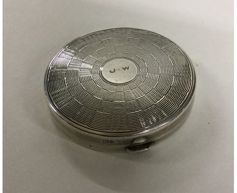 A small circular silver engine turned box with hinged top. Approx. 32 grams. Est. £25 - £35.