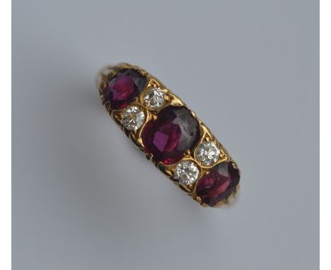 A ruby and diamond seven stone ring in carved mount. Approx. 4.4 grams. Est. £800 - £1200.