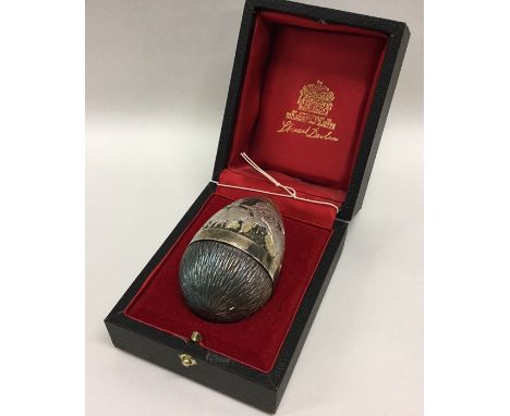 STUART DEVLIN: An unusual cased silver egg of typical design with lift off cover revealing angels, figures and animals. Appro