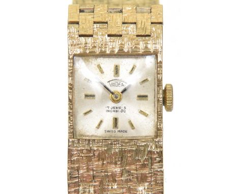 A 9ct gold ladies Trident wristwatchThe square shaped champagne dial with baton hour markers signed Trident, inset to the tex