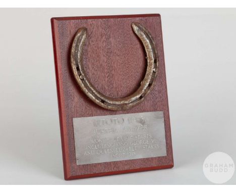 Shoe worn by the racehorse Mtoto,mounted on a wooden plaque with easel support and set with an engraved metal plaque, 20 by 1
