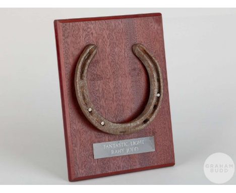Shoe worn by the racehorse Fantastic Light,mounted on a wooden plaque with easel support and set with an engraved metal plaqu