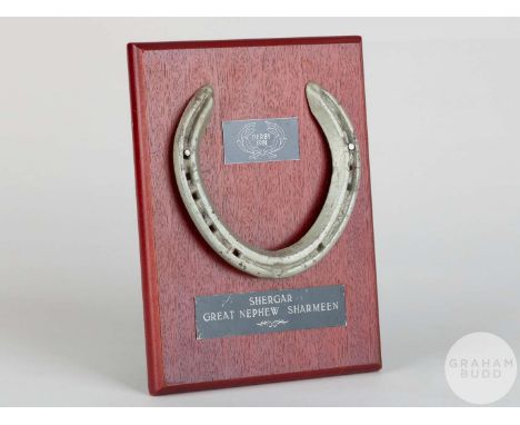 Shoe worn by the racehorse Shergar,mounted on a wooden plaque with easel support and set with engraved metal plaques, 20 by 1