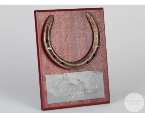 Shoe worn by the racehorse Shernazar,mounted on a wooden plaque with easel support and set with an engraved metal plaque, 20 