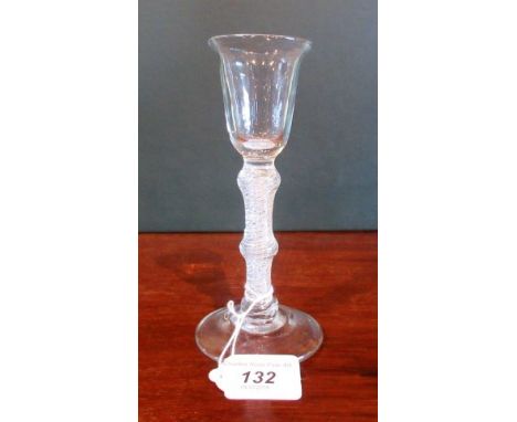 A 19th century drinking glass with bell shaped bowl, whirlpool knop stem on stepped conical base, 17cm tall.