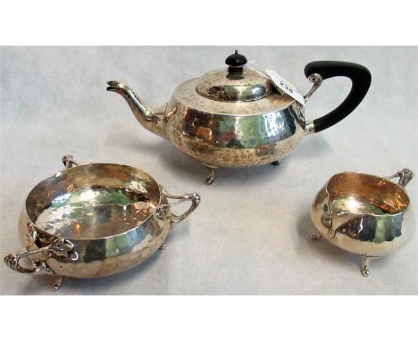 A three piece tea set, to include: teapot, milk jug and sugar bowl, each of circular design with hammered decoration to jug a