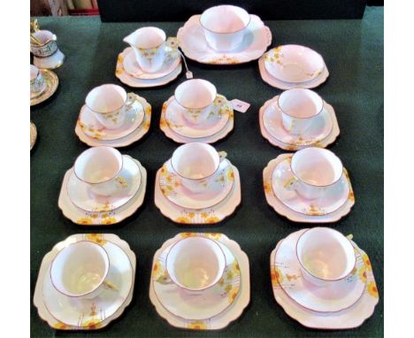 A Melba bone china tea service in the Art Deco style, comprising: nine trios, cake plate, sugar bowl and cream jug.