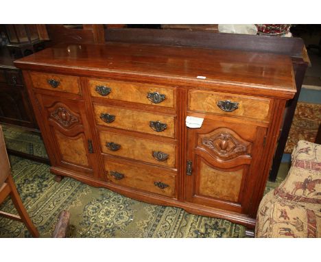 An art nouveau Walnut Sideboard, having moulded edge rectangular top over central flight of four graduated burr fronted drawe