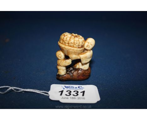 A mid 19th c. Japanese Netsuke, depicting a man and a boy carrying a basket containing a pumpkin, (the base possibly repaired