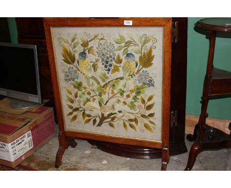 An arts and crafts Oak Firescreen, handle to the top, the front having tapestry depicting parrots and squirrel amongst foliag