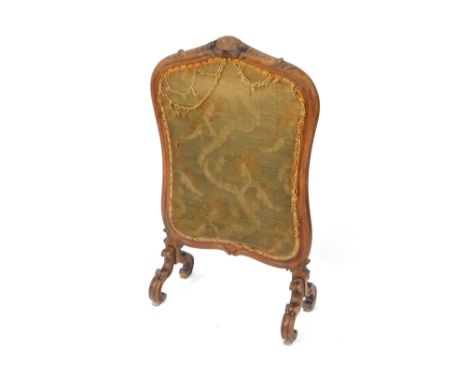 A Victorian mahogany fire screen, fabric in a shield shaped frame, carved with a shell flowers and leaves, raised on four flu