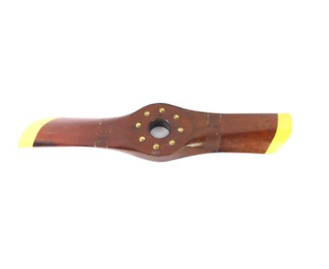 A vintage mahogany propeller, with brass stud work, painted yellow wing tips, 87cm W.