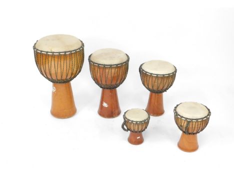 Five graduated wooden and hide bongo drums, with coloured rope twist binding, largest drum 61cm H, smallest drum 23cm H.