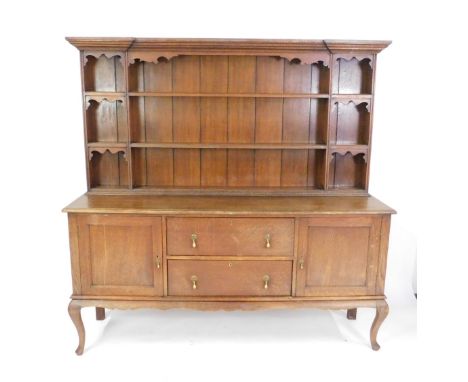 A Victorian oak dresser, the outswept pediment over a three shelf plate rack, flanked by six recesses, above two deep drawers