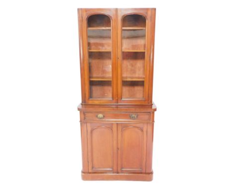 A Victorian mahogany bow front cupboard bookcase, pediment lacking, with two glazed doors, opening to reveal three shelves, o