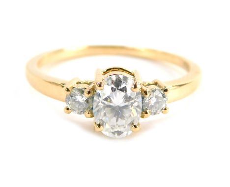 A three stone dress ring, set with three moissanites, comprising a large oval moissanite in four claw setting flanked by two 