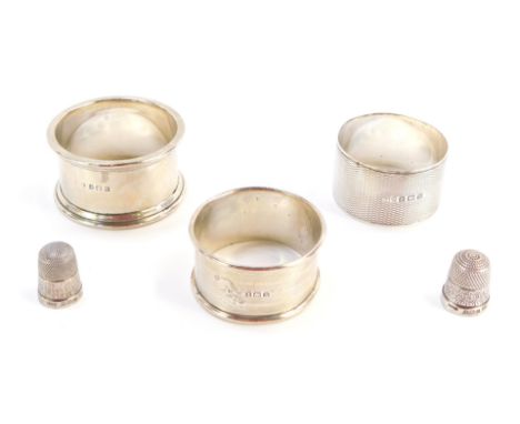 Three silver napkins rings and two silver thimbles, the napkin ring George VIII and later, one with engine turned hatch detai