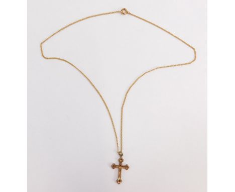 A crucifix pendant and chain, the crucifix with floral scroll decoration and single loop top, on a fine link chain, stamped 9