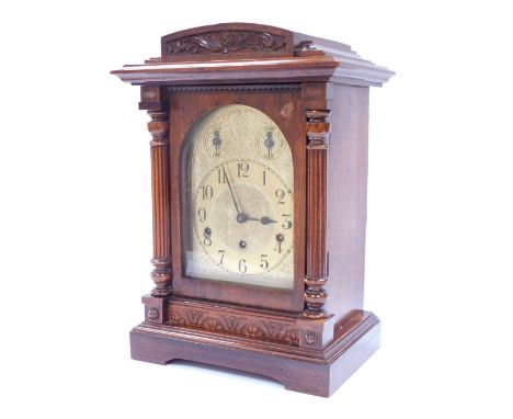 An early 20thC oak cased mantel clock, with arched pediment top and two column support, with a brass dial with Westminster ch