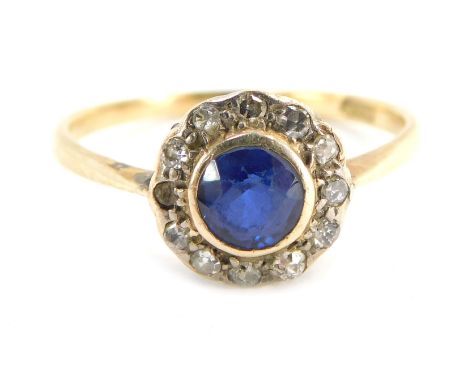 A sapphire and diamond cluster ring, the central round brilliant cut sapphire in rub over setting, surrounded by tiny diamond