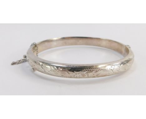 A Victorian silver hinged bangle, the half hinged designed with engraved scroll decoration and safety chain, 6cm diameter.