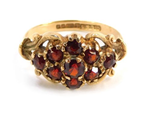 A 9ct gold dress ring, the cluster section set with garnets with scroll design shoulders, size L½, 3.2g all in.