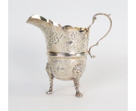 An Edwardian silver helmet shape cream jug, raised on three lion mask legs with paw feet, London 1909, 145grams. 